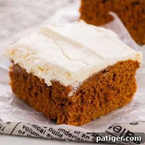2-ingredient pumpkin spice cake with cream cheese frosting sliced into a square.