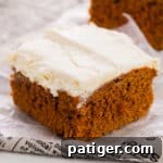 2-ingredient pumpkin spice cake with cream cheese frosting sliced into a square.