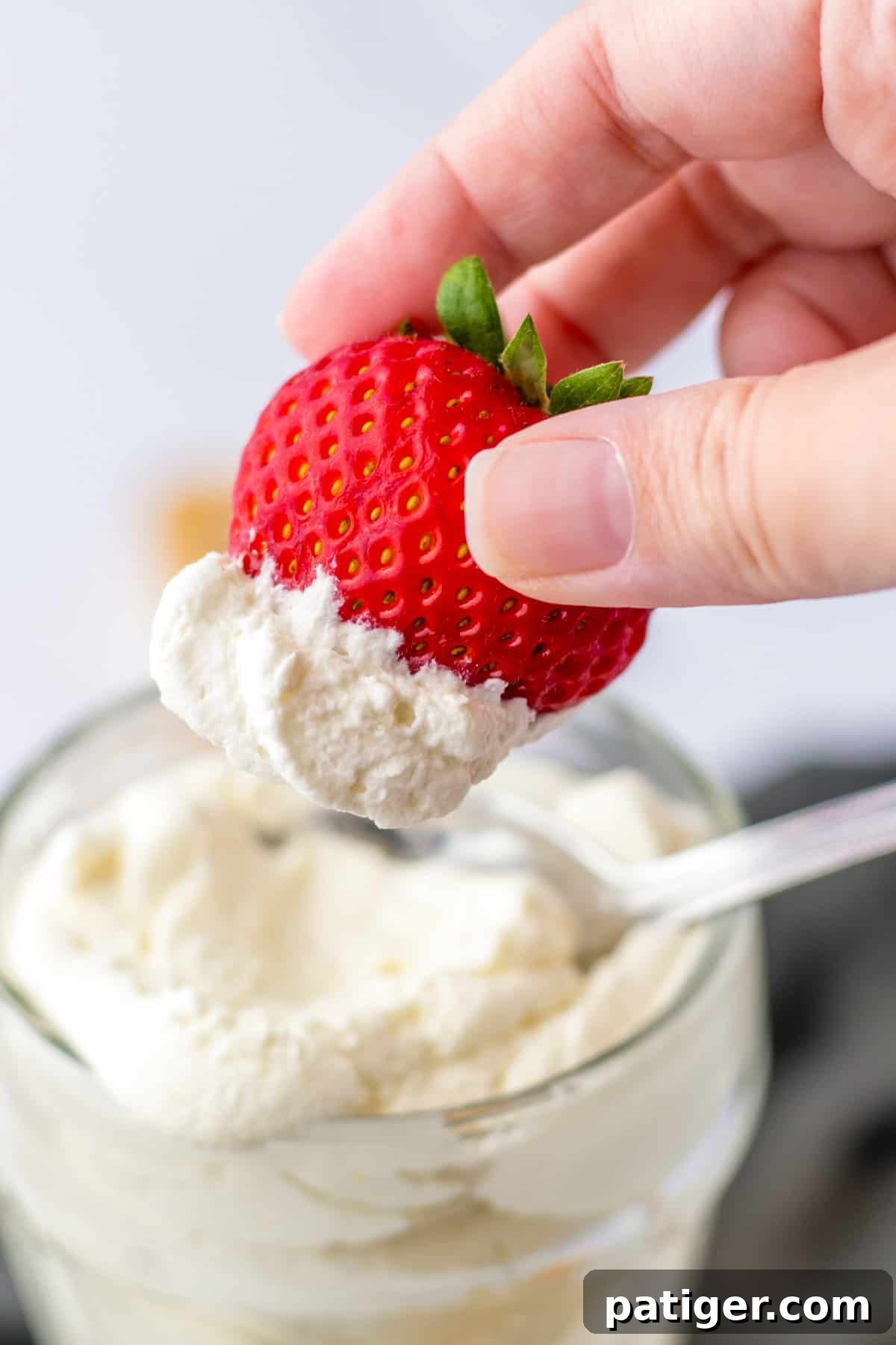 Light and fluffy homemade cool whip whipped topping generously dolloped on a fresh strawberry.