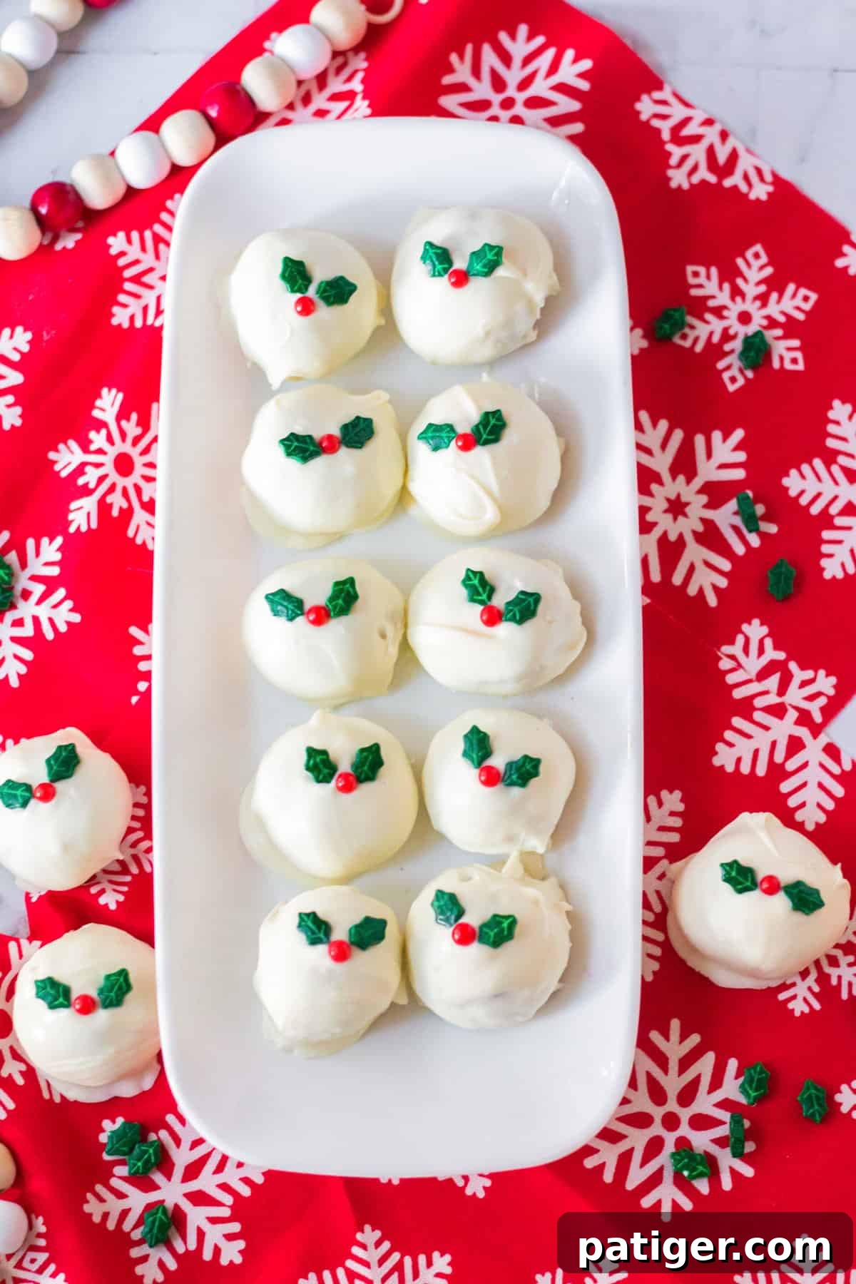 Tray of white chocolate golden oreo truffles topped with holly candies.