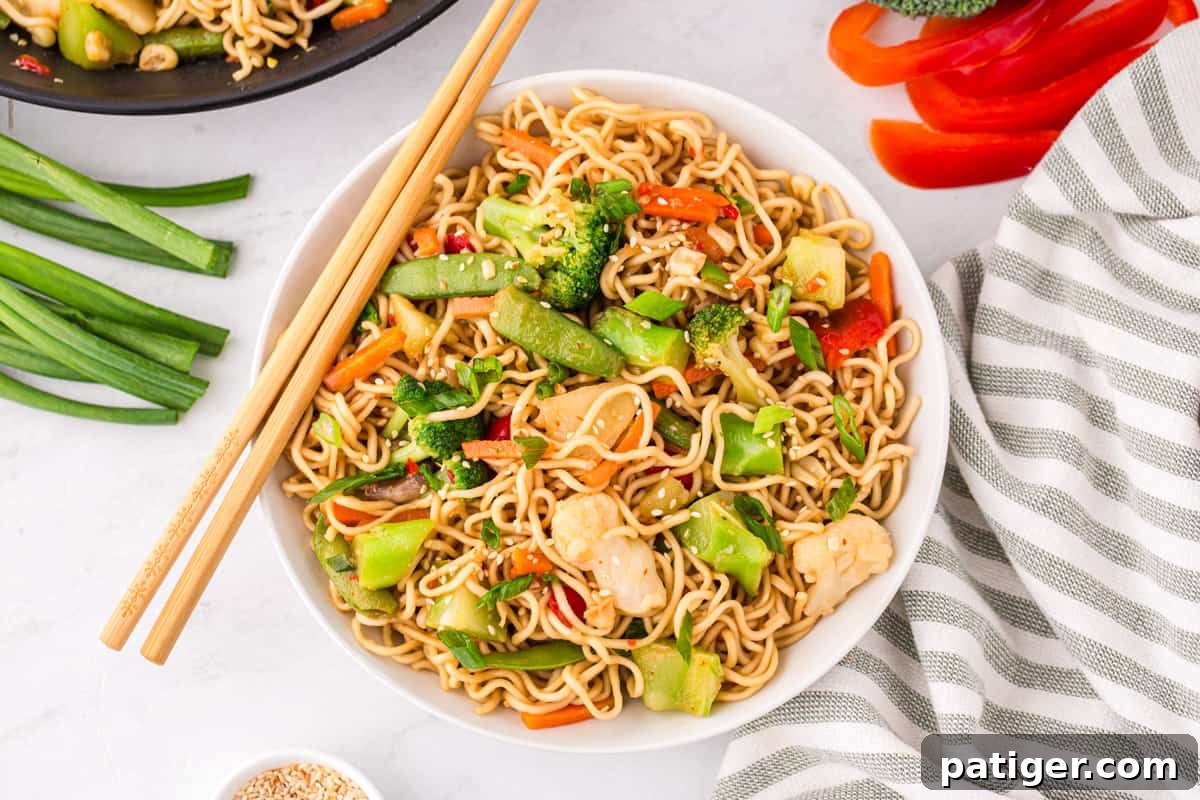 A delicious bowl of stir-fry ramen with an abundance of colorful vegetables, perfectly prepared and served with a pair of chopsticks for an authentic and satisfying dining experience.