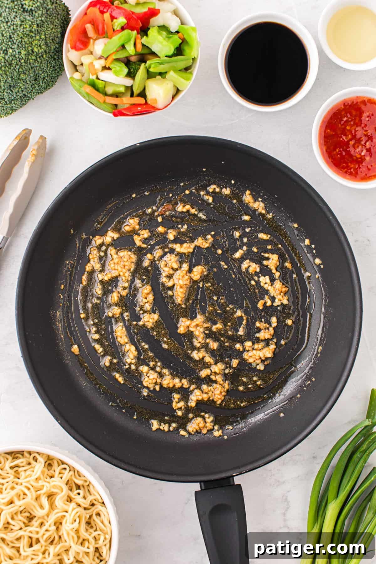Minced garlic being expertly sautéed in a large frying pan, emitting a delightful, fragrant aroma, after cooking for approximately one minute to release its full flavor.