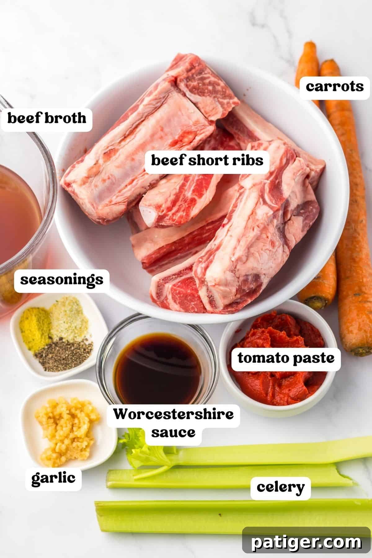 A selection of raw beef short ribs, beef broth, chopped carrots, celery, tomato paste, minced garlic, Worcestershire sauce, and seasonings laid out on a countertop, ready for cooking.