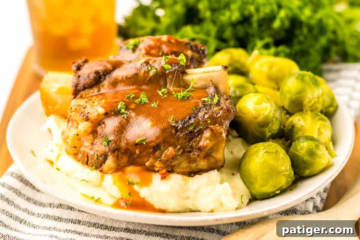 Crock Pot Beef Short Ribs served with mashed potatoes, brussel sprouts, and a side of the rich gravy.