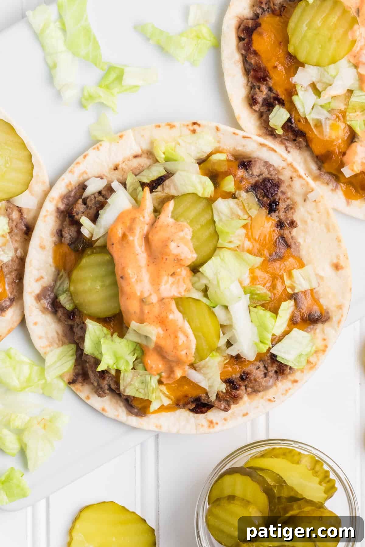 Close-up of a Big Mac smash burger taco, generously topped with shredded lettuce, tangy pickles, and a drizzle of the secret sauce.