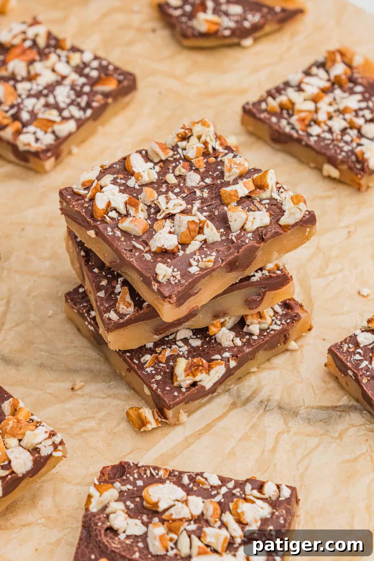 Homemade English toffee topped with chopped pecans and chocolate, showing the golden toffee layer beneath.