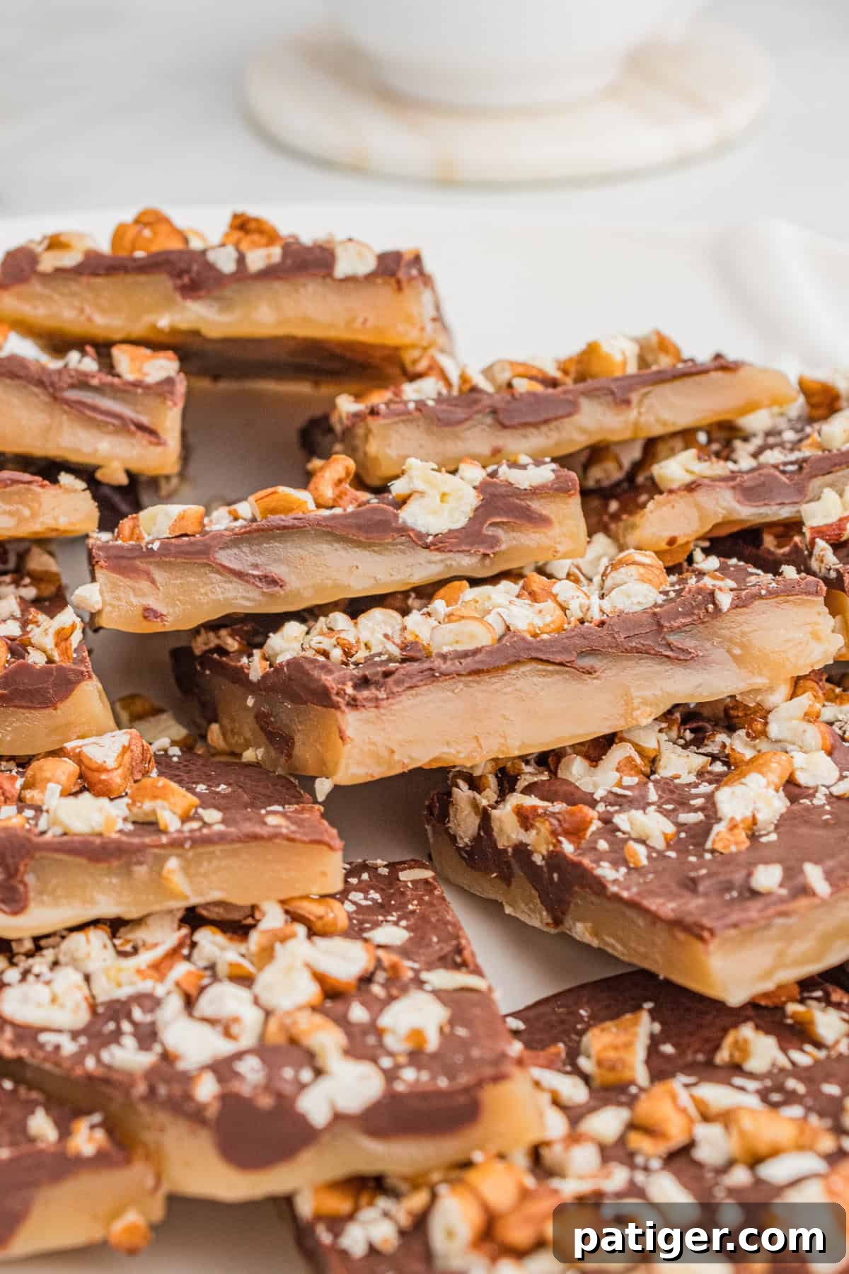 Chocolate-covered toffee candy squares with visible layers of toffee and chocolate, topped with crushed pecans for a crunchy finish.