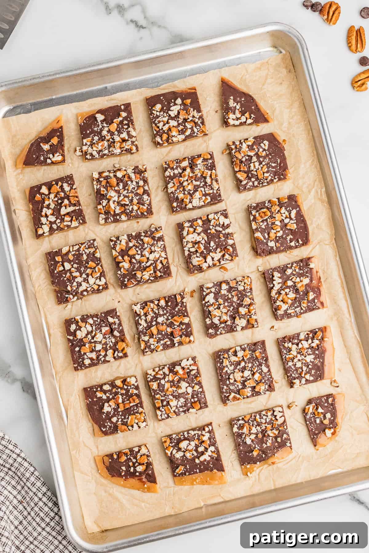 Classic English toffee sliced into squares on a parchment paper lined metal baking sheet.