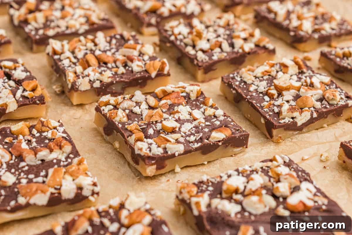 Homemade English toffee candy squares topped with melted chocolate and chopped pecans, arranged neatly on a parchment-lined baking sheet.