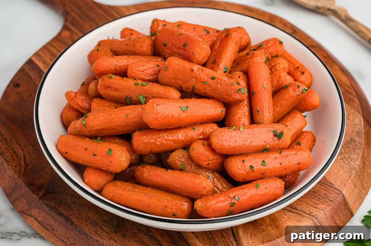 A beautifully arranged bowl of glossy brown sugar honey glazed baby carrots on a rustic wooden serving board, ready to be enjoyed as a delightful side dish.