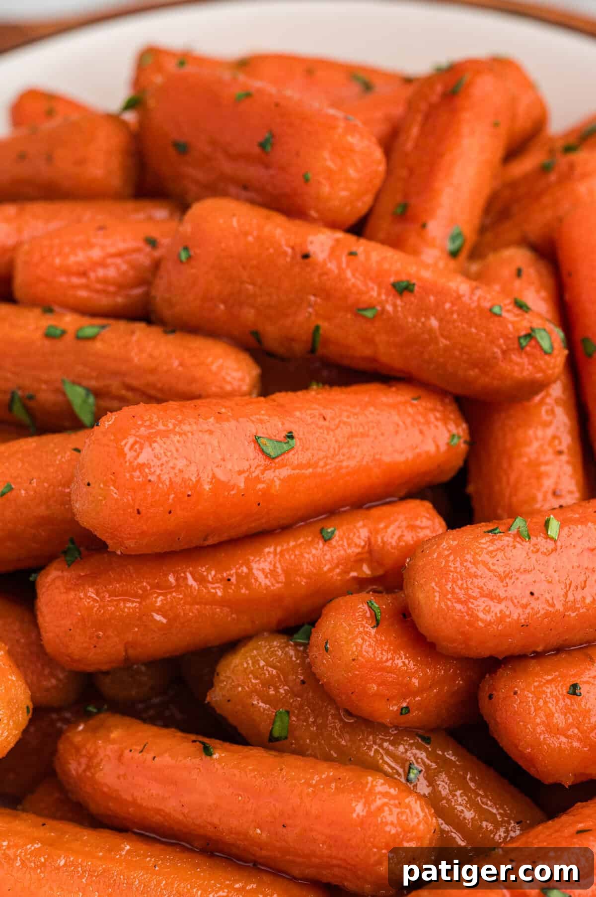 A close-up of beautifully roasted brown sugar honey glazed carrots, elegantly garnished with vibrant chopped fresh herbs for an appealing presentation.