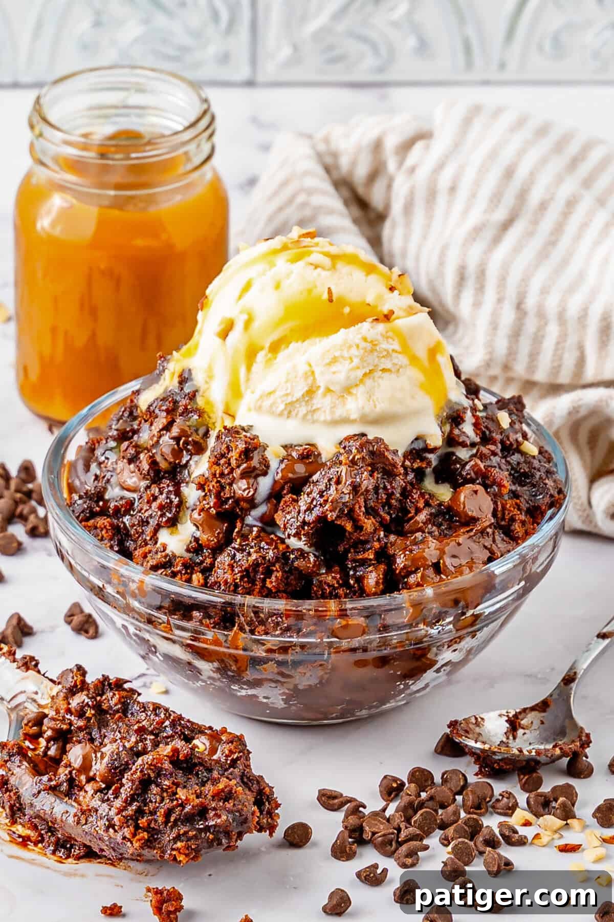 Chocolate dump cake served warm in a bowl with a scoop of vanilla ice cream and a luscious caramel drizzle.