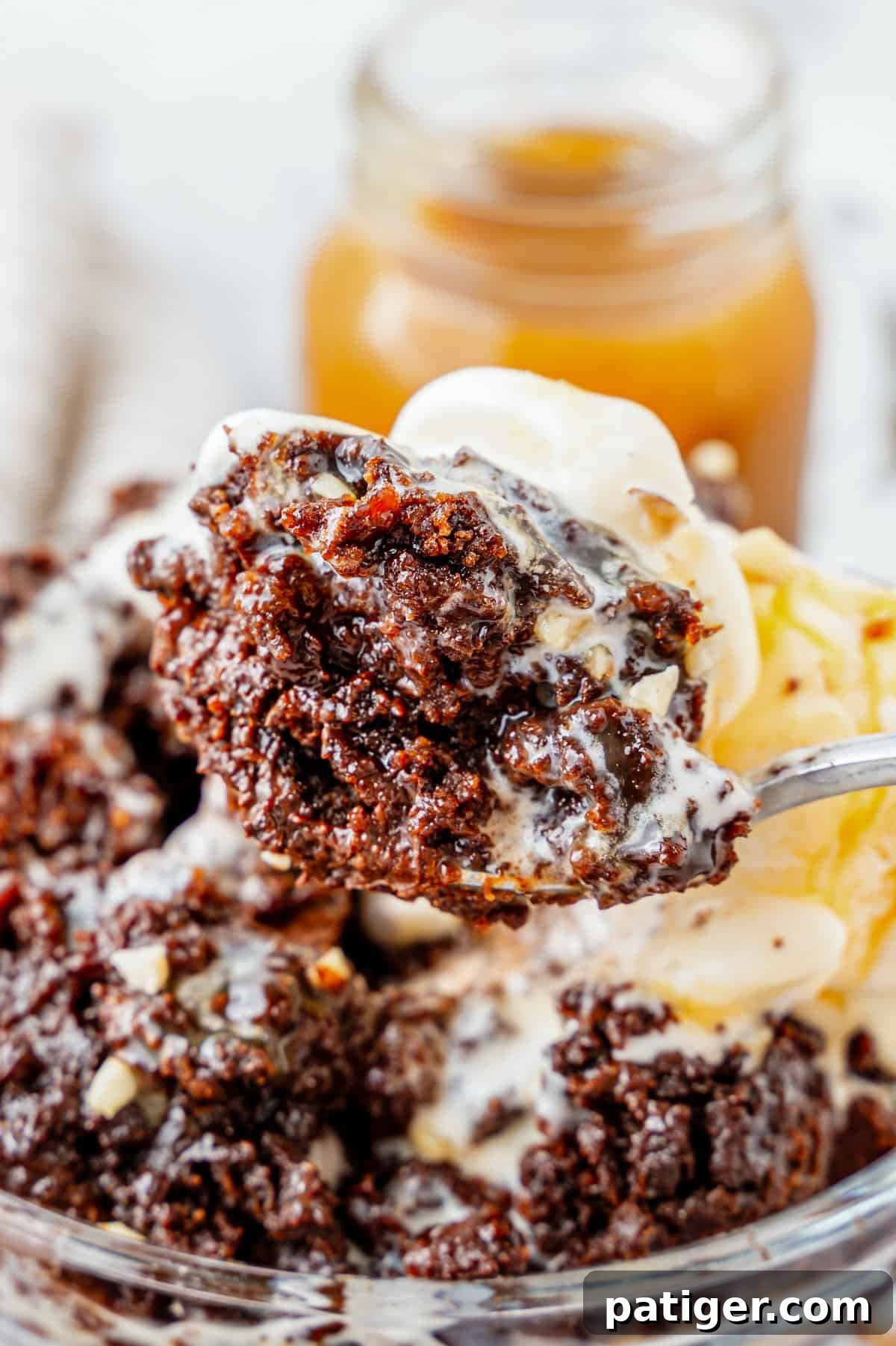 A spoon delicately holding a perfect bite of warm chocolate dump cake alongside a melting scoop of vanilla ice cream.