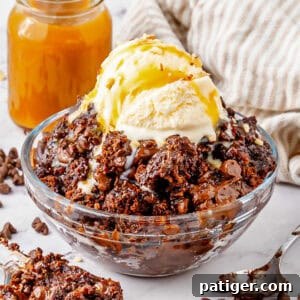 Bowl of chocolate dump cake with chocolate chips, chocolate syrup, and scoop of vanilla ice cream.