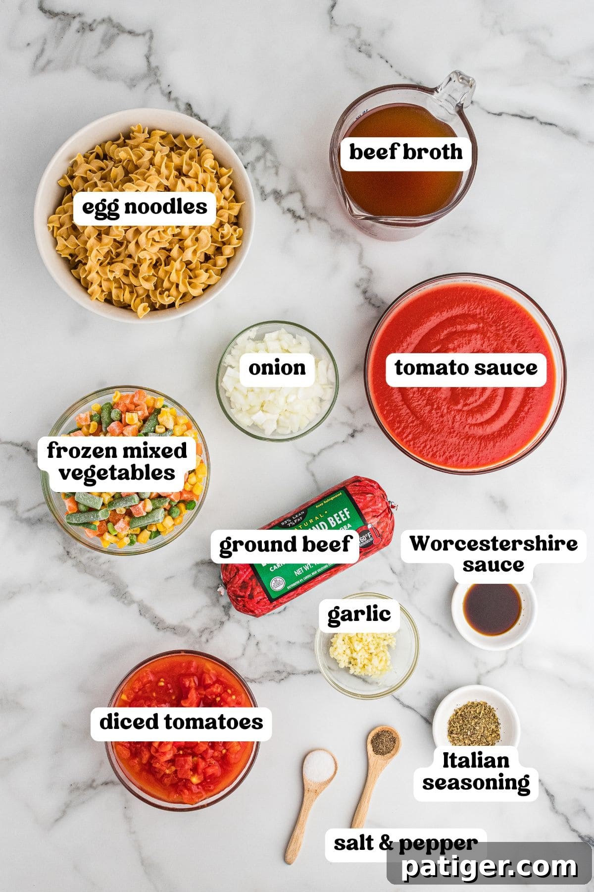 Ingredients for hamburger noodle soup laid out: egg noodles, lean ground beef, diced tomatoes, tomato sauce, beef broth, frozen mixed vegetables, chopped onion, minced garlic, Worcestershire sauce, Italian seasoning, and salt and pepper.