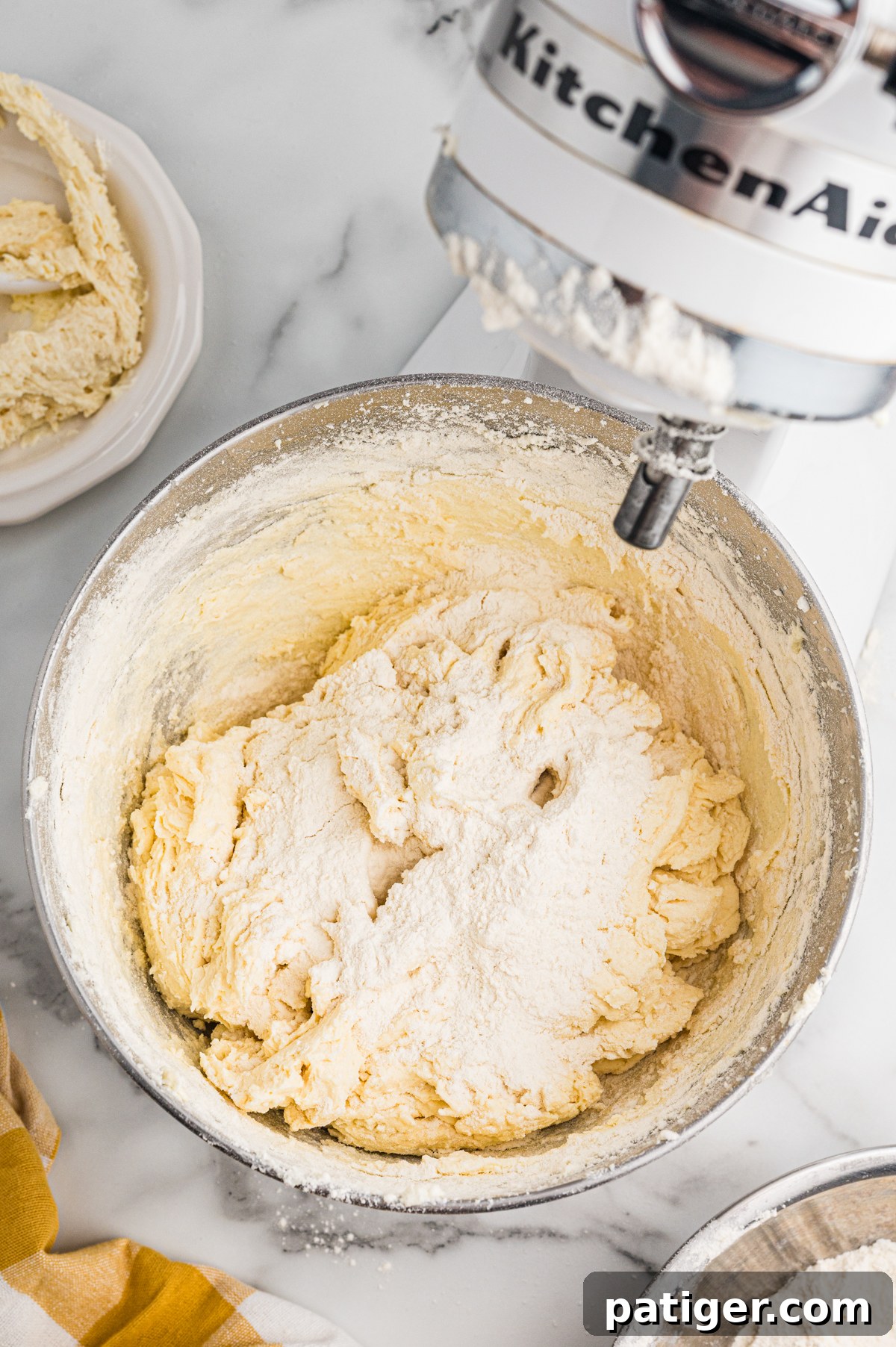 Flour added to thick batter in stand mixer bowl.