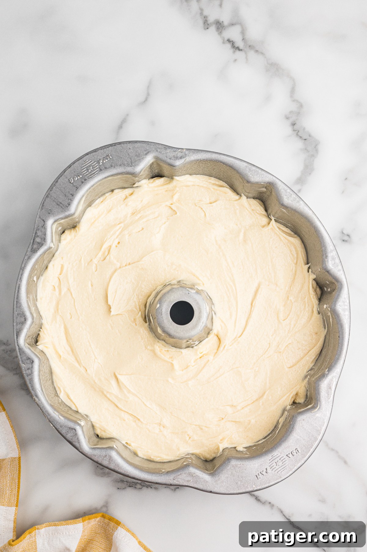 Unbaked 7 Up pound cake batter is evenly spread in a silver fluted Bundt pan.