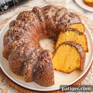 Rum cake recipe with cake mix sliced on a white plate with glaze and chopped pecans on top.