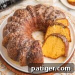 Rum cake recipe with cake mix sliced on a white plate with glaze and chopped pecans on top.