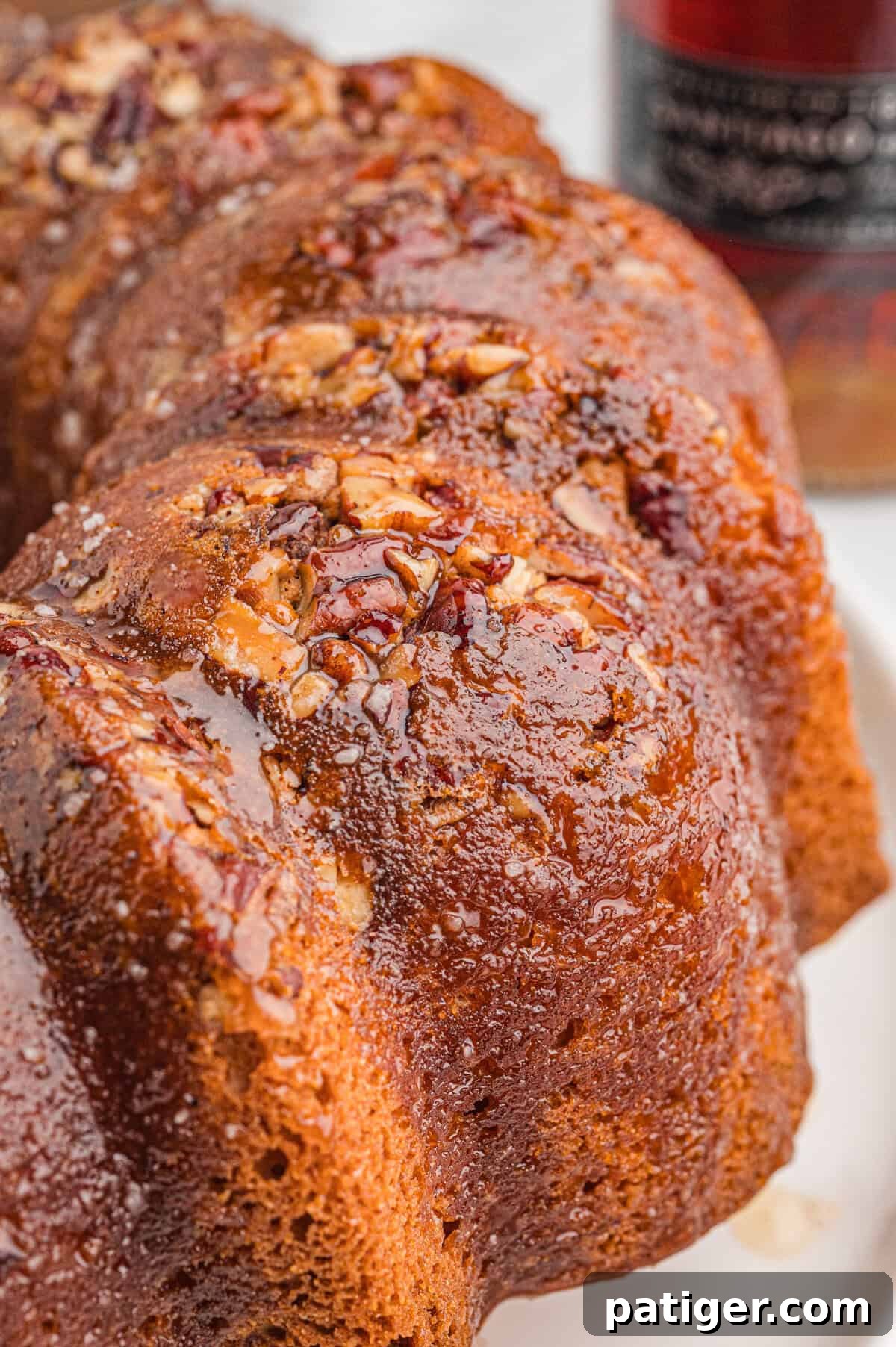 Close-up of a rum bundt cake with glossy glaze and chopped pecans on top.