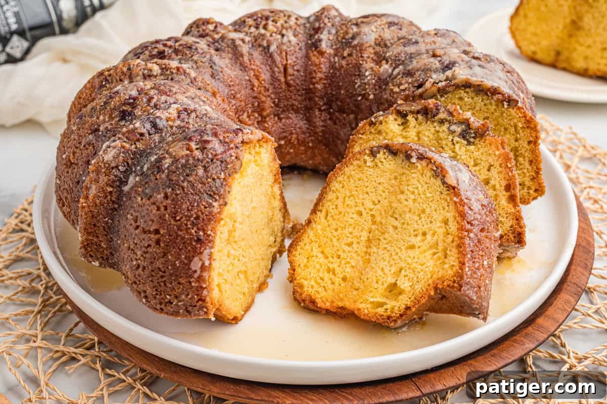 Glazed rum bundt cake on a white plate with slices cut showing the golden crumb.