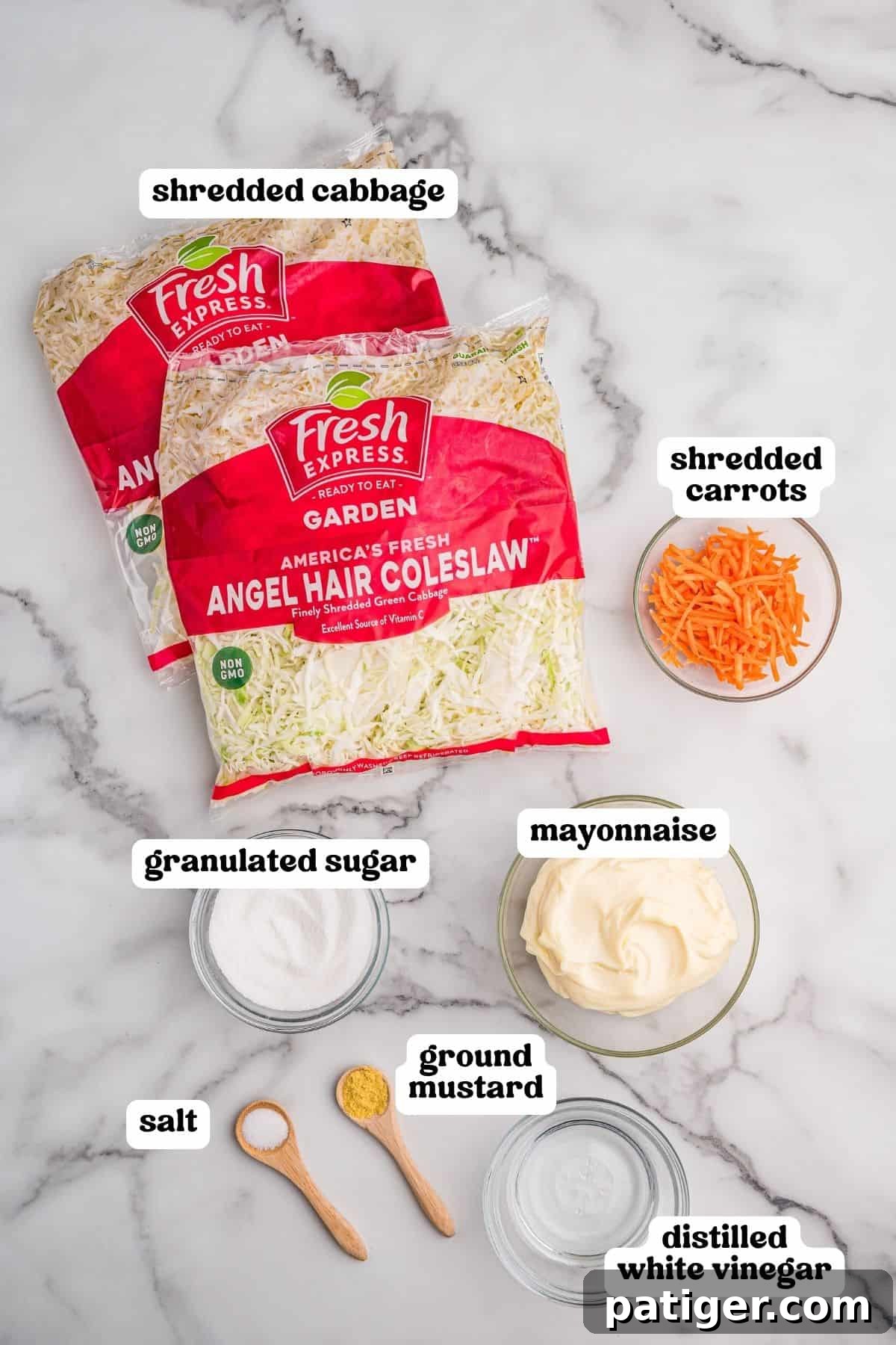 Ingredients on a marble counter: bagged angel hair coleslaw, shredded carrots, sugar, mayonnaise, salt, ground mustard, and white vinegar.