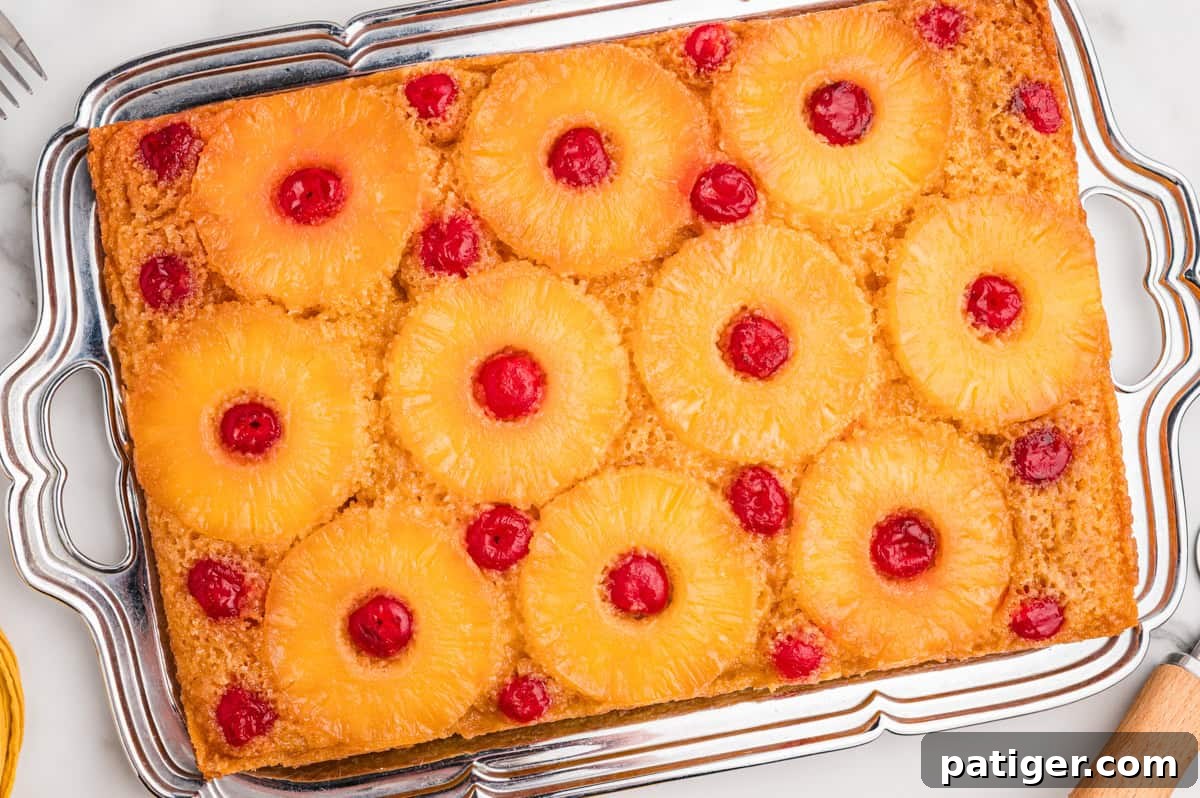 Pineapple upside down cake with cake mix on a white platter, topped with pineapple rings and maraschino cherries.