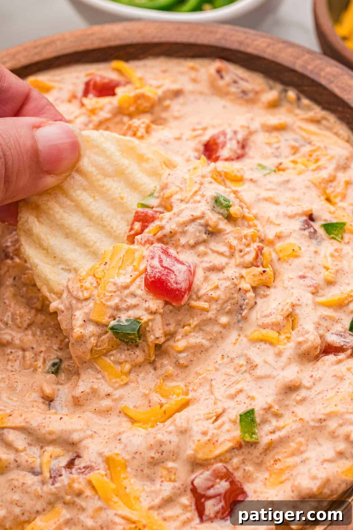 How to Swim Safely from Your Boat 2 A hand scooping creamy dip from a wooden bowl with a ruffled potato chip.