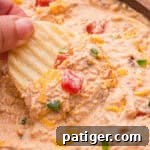 How to Swim Safely from Your Boat 7 A ruffled potato chip held up with a scoop of dip, diced tomatoes, and shredded cheddar.