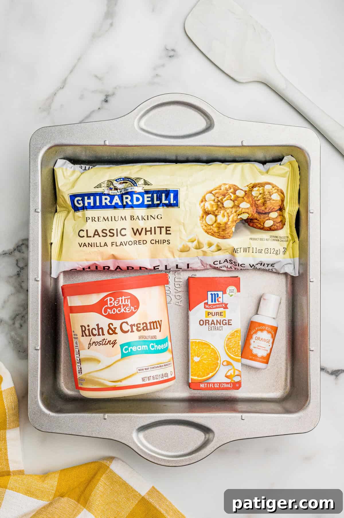 Creamsicle Orange Fudge Recipe 3 Ingredients in a metal pan: Ghirardelli white chocolate chips, cream cheese frosting, orange extract, and orange food coloring.
