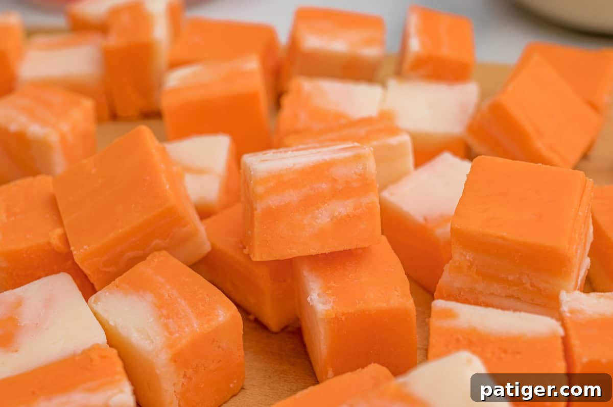 Creamsicle Orange Fudge Recipe 7 Close-up of orange and white fudge squares scattered on a wood cutting board.