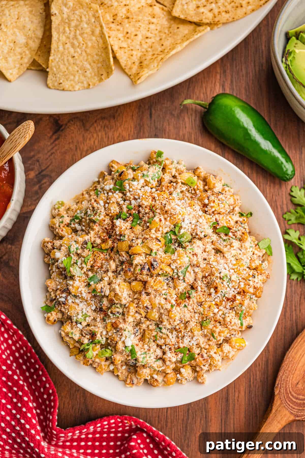 Creamy Mexican Street Corn Dip with Cotija and Lime 6 Overhead view of easy street corn dip in a white bowl topped with cotija and chili powder, chips alongside.