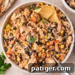 Overhead bowl of southwest chicken salad with black beans, corn, peppers, and a tortilla chip.