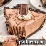 A slice of Hershey pie with an Oreo crust, topped with whipped cream, a Hershey's bar, and chocolate shavings.