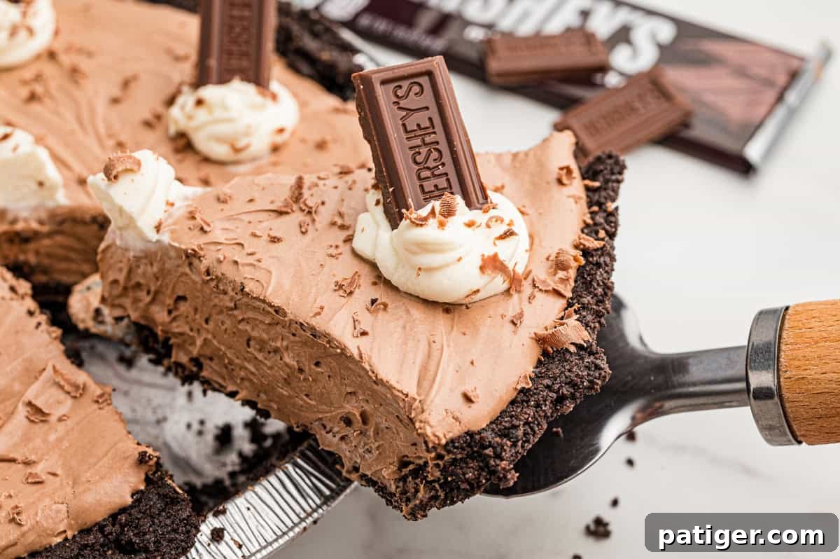 Homemade Hershey's Chocolate Pie Recipe 8 A slice of pie lifted on a pie server, with Hershey's bars and the rest of the pie behind.