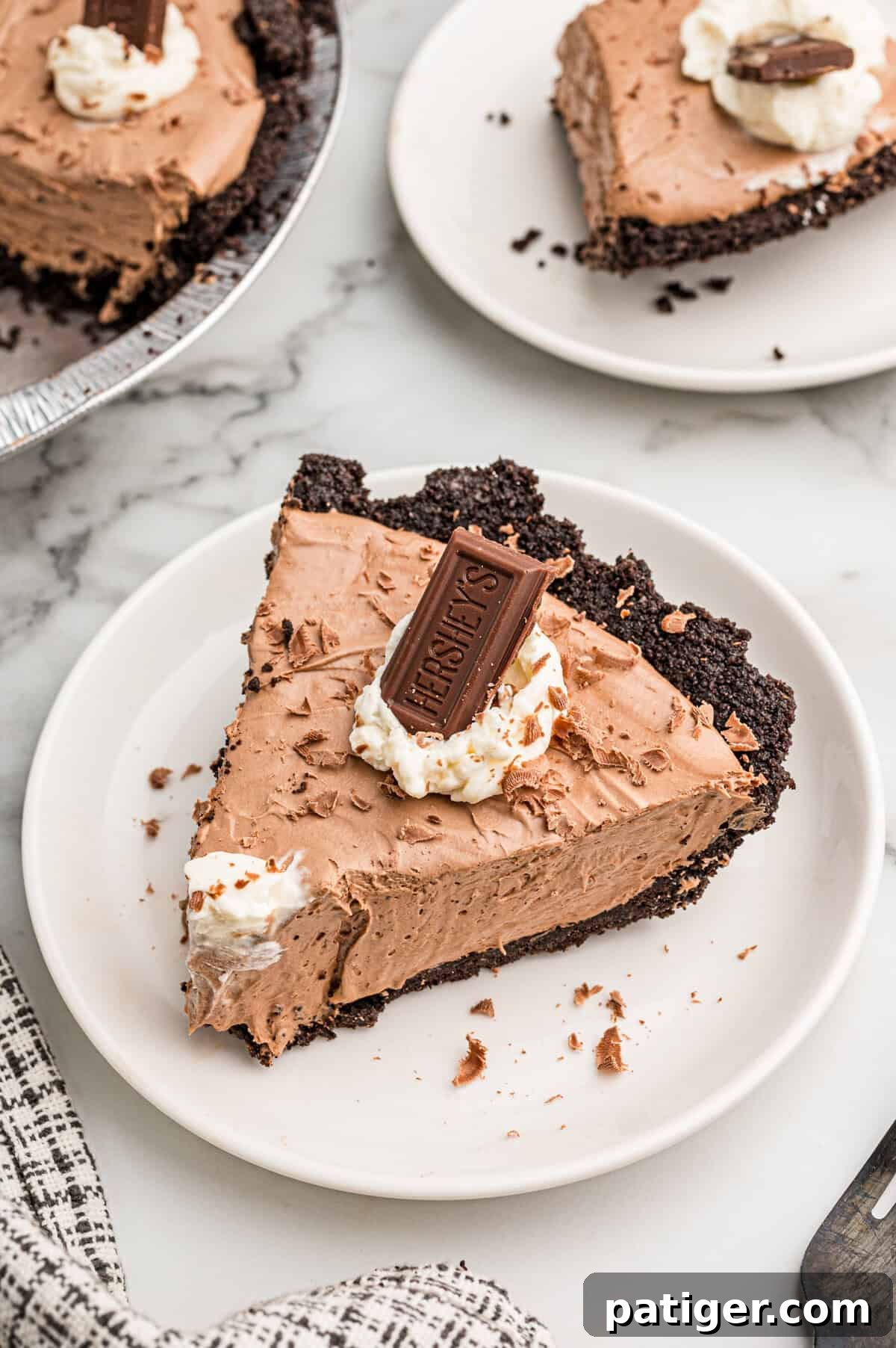 Homemade Hershey's Chocolate Pie Recipe 9 A slice of chocolate pie on a white plate with a second plated slice and the pie behind it.