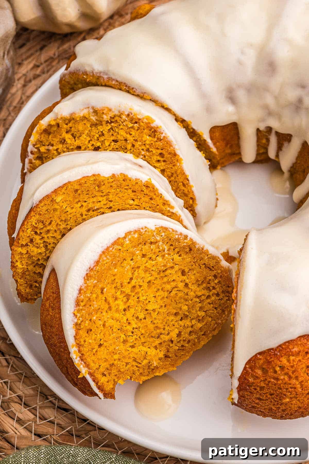 Moist Pumpkin Bundt Cake Made with Cake Mix 2 Overhead view of four glazed pumpkin cake slices fanned across a white plate.