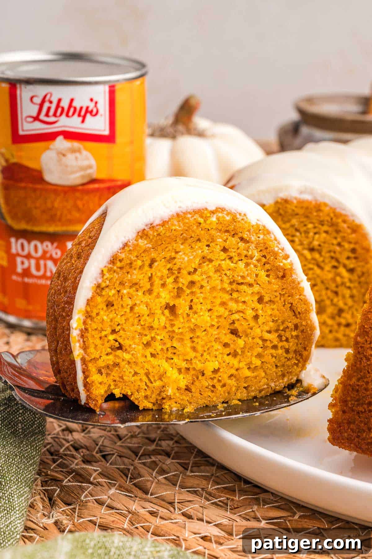 Moist Pumpkin Bundt Cake Made with Cake Mix 11 A glazed slice of pumpkin cake lifted on a cake server with a can of Libby's pure pumpkin behind it.