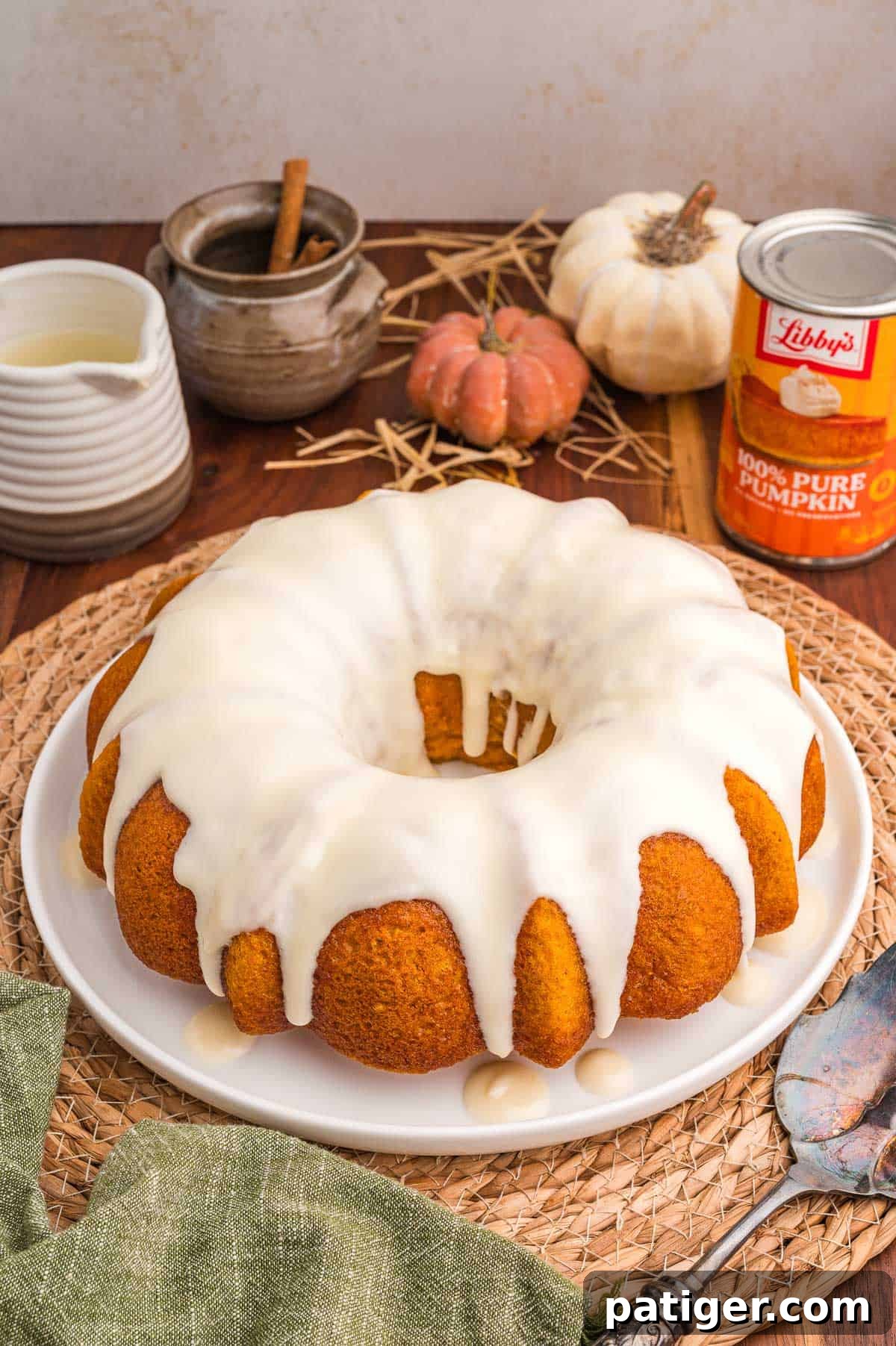 Moist Pumpkin Bundt Cake Made with Cake Mix 3 Pumpkin bundt cake with cake mix on a white plate with cream cheese glaze, small pumpkins and a can of pumpkin behind it.