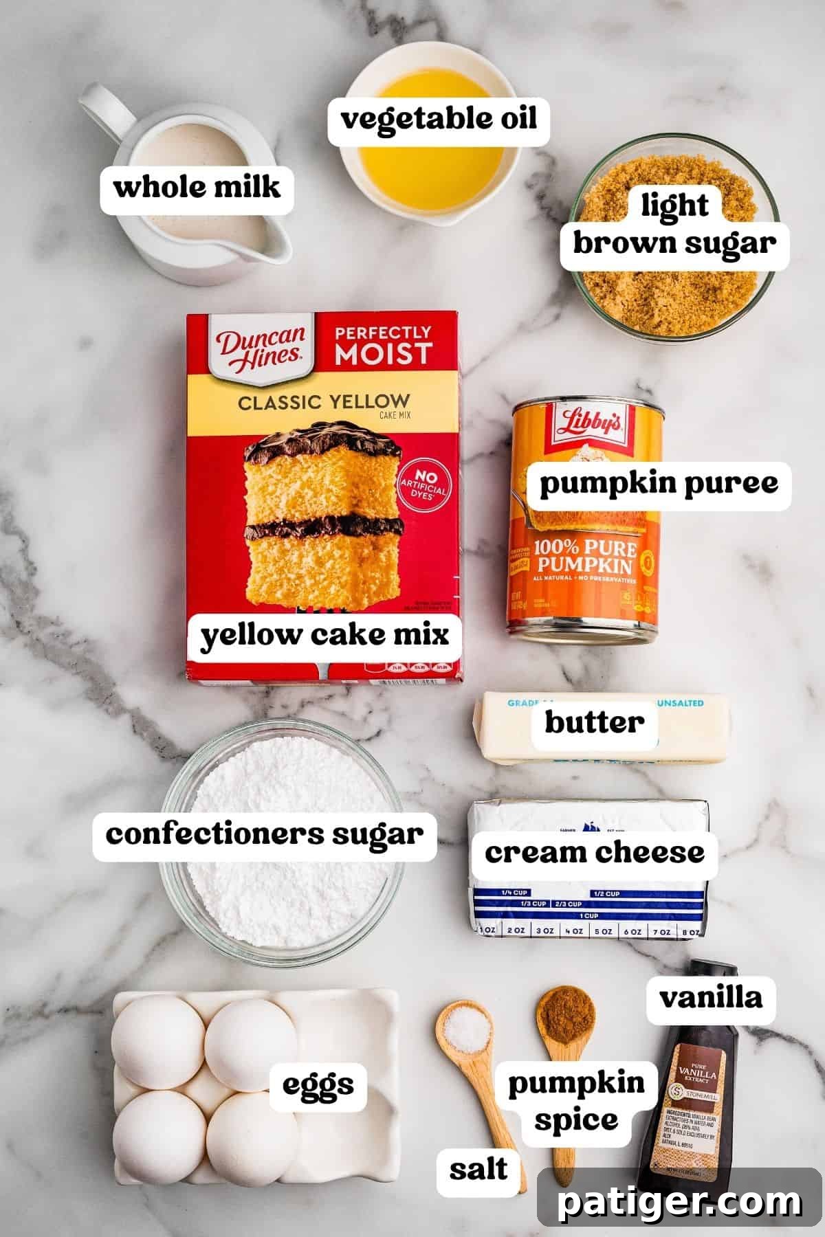 Moist Pumpkin Bundt Cake Made with Cake Mix 4 Labeled ingredients on marble: yellow cake mix, pumpkin puree, eggs, brown sugar, oil, milk, butter, cream cheese, and pumpkin spice.