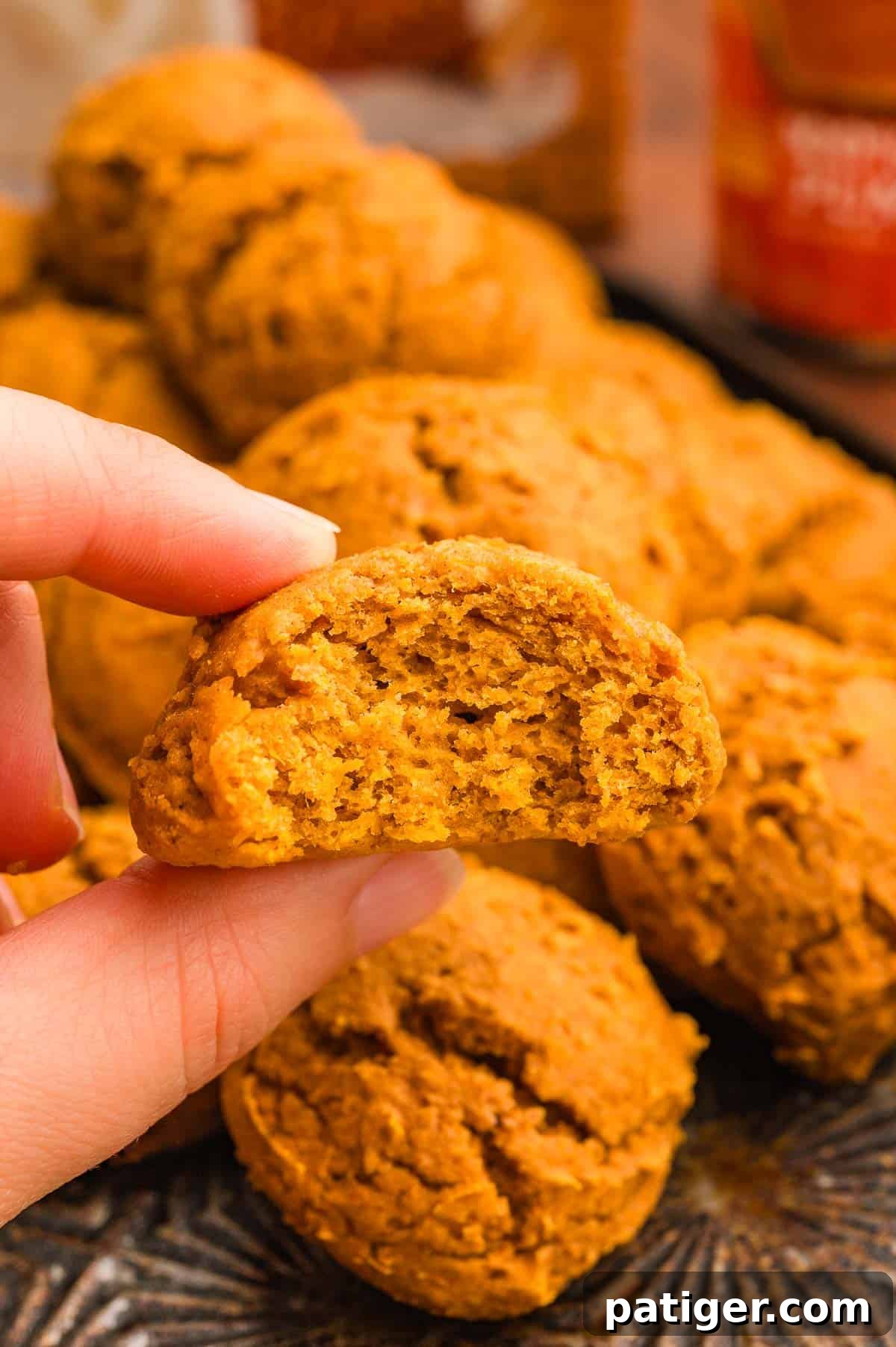 Cake Mix Pumpkin Cookies: Soft Spiced Fall Treats 3 A hand holding a pumpkin cookie with a bite taken out, showing the soft cakey inside.
