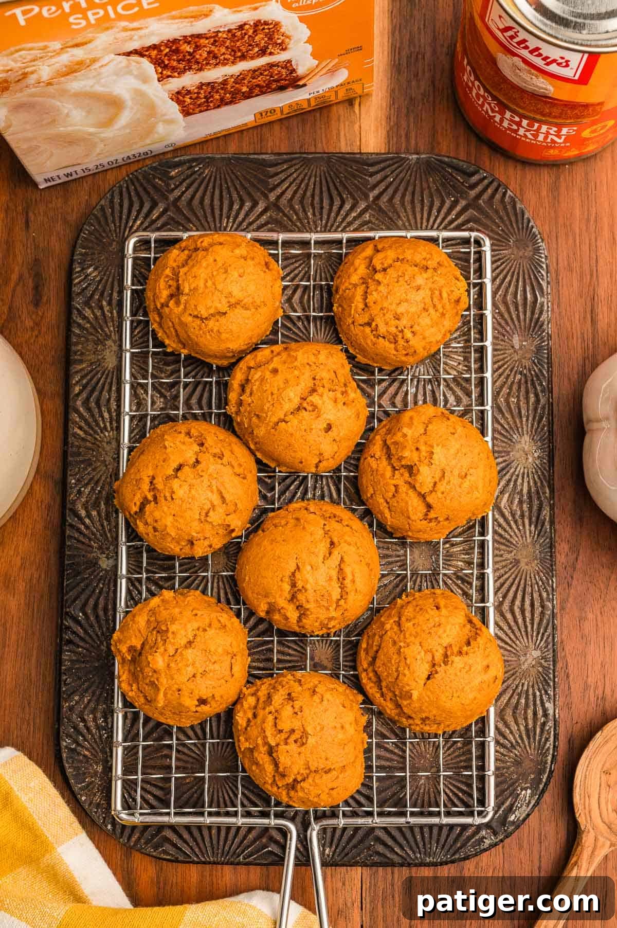 Cake Mix Pumpkin Cookies: Soft Spiced Fall Treats 8 Pumpkin cookies on a wire rack over a dark pan, with a cake mix box, pumpkin can, and wooden spoon nearby.
