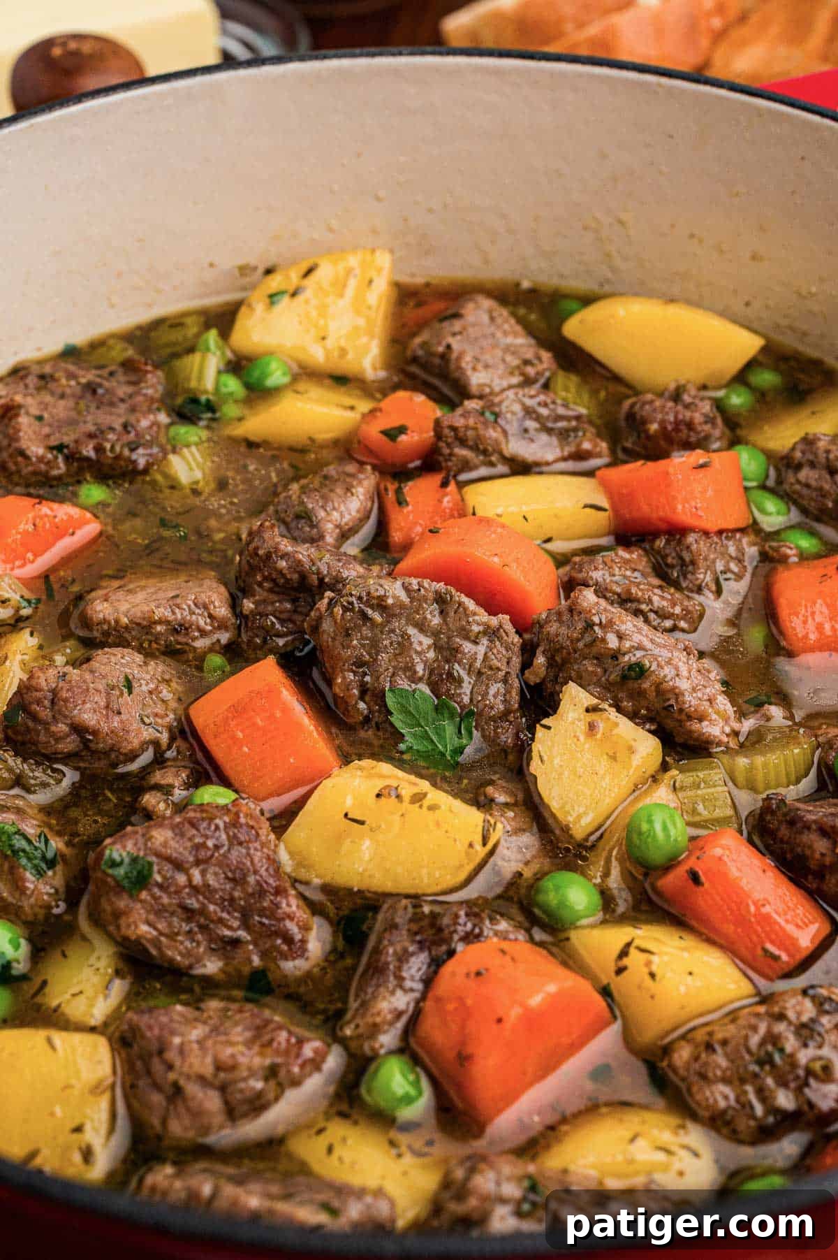 Classic Hearty Beef Stew Recipe with Tender Braised Beef 6 Close-up of beef stew in a pot with chunks of beef, carrots, potatoes, peas, and parsley.