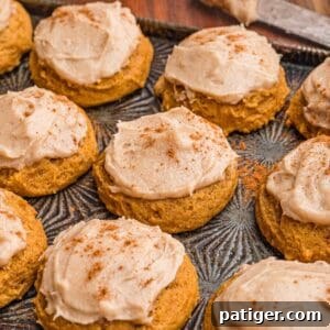 Frosted pumpkin cookies dusted with cinnamon.