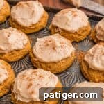 Frosted pumpkin cookies dusted with cinnamon.