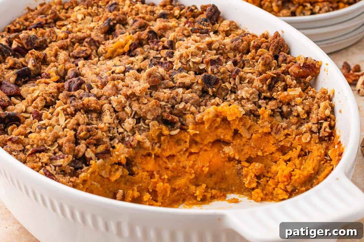 Baked sweet potato casserole in a white dish with a scoop taken out, showing the orange filling.