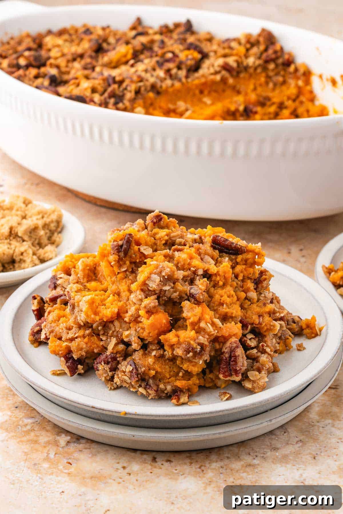A plate of canned yam sweet potato casserole in front of the baking dish it was scooped from.