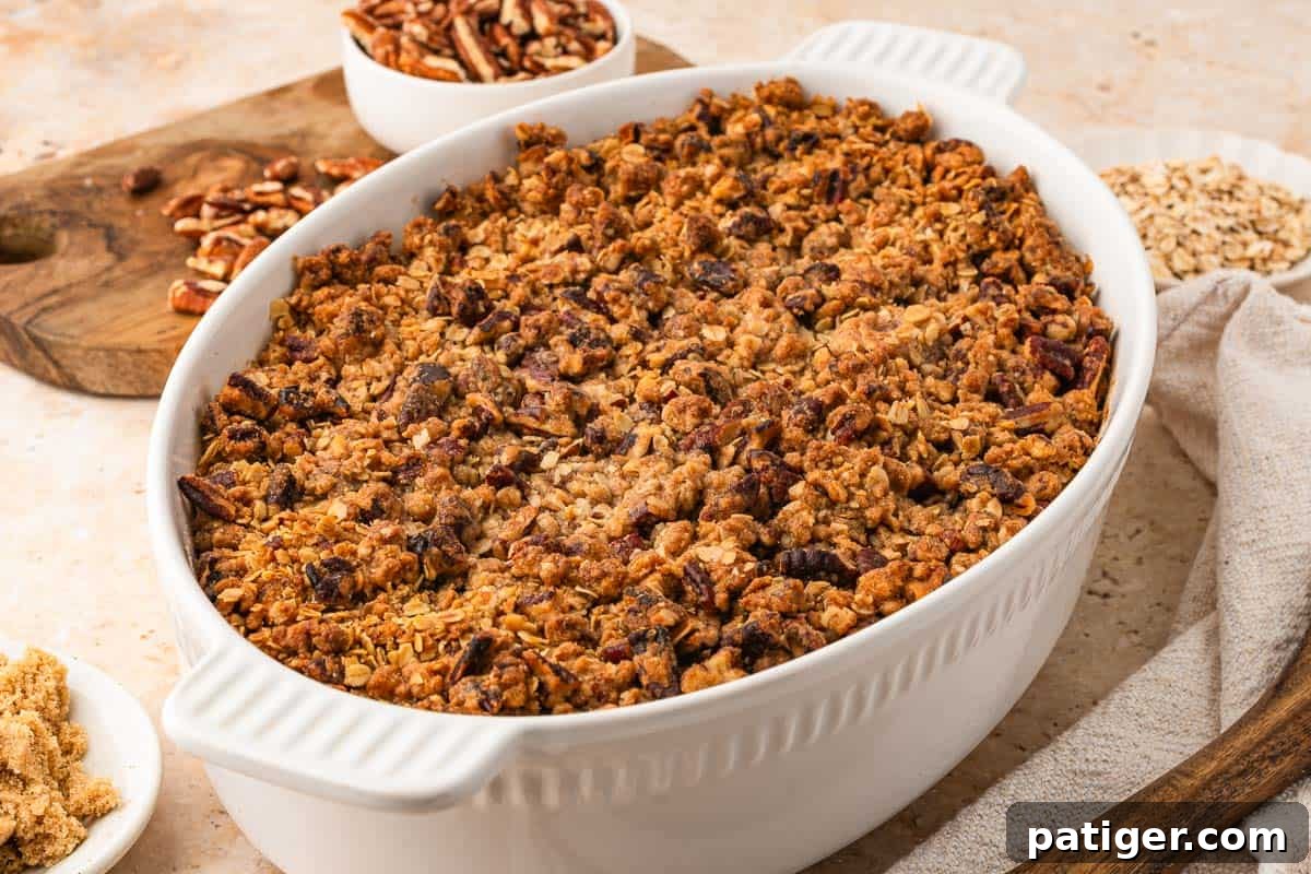 Sweet potato casserole with canned yams in a white oval baking dish, topped with a golden pecan oat streusel.