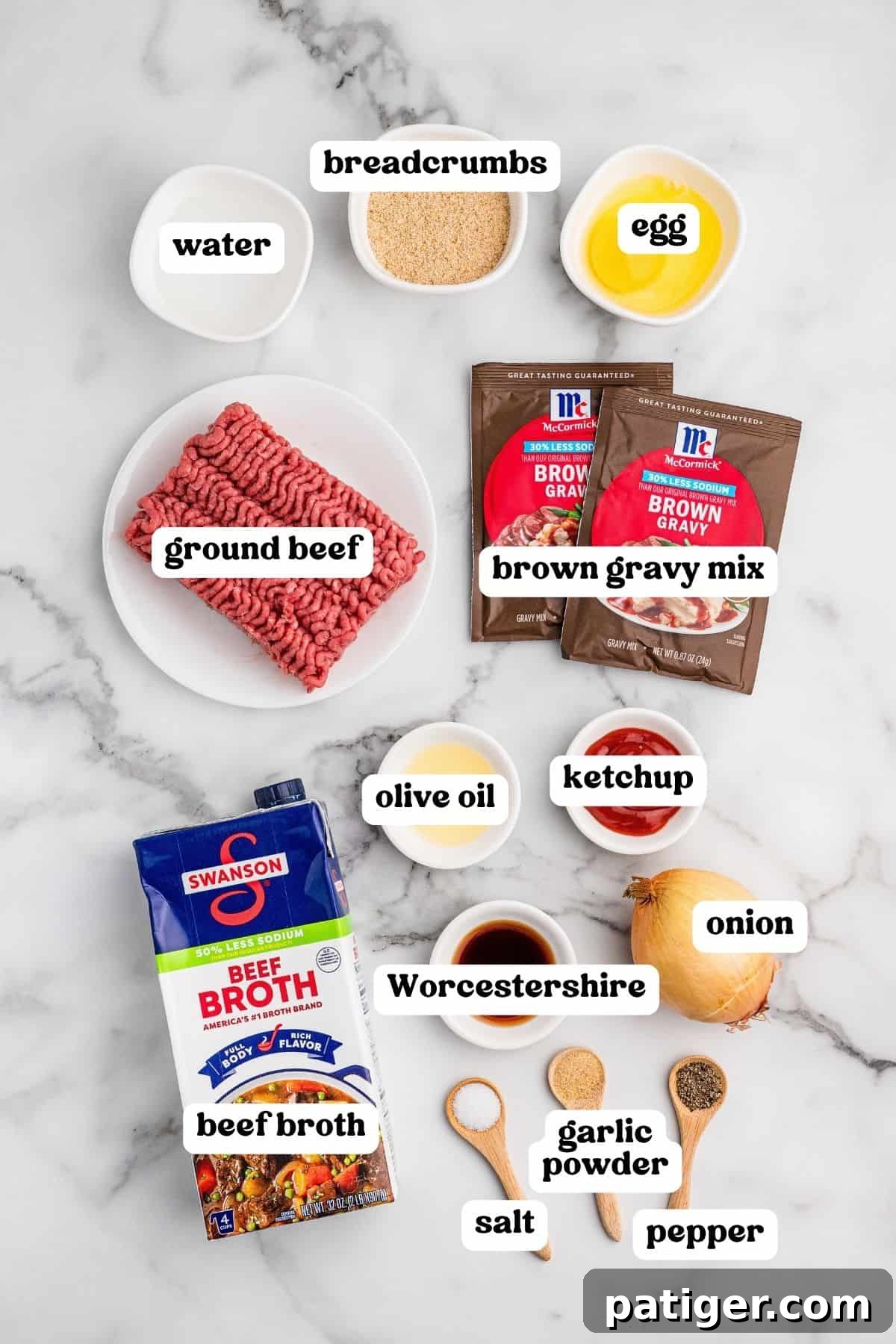 Ingredients on marble: ground beef, egg, breadcrumbs, brown gravy packets, beef broth, ketchup, Worcestershire, olive oil, onion, and seasonings.